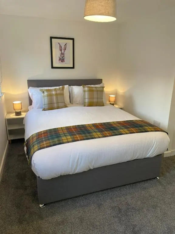 a bedroom with a large bed with two lamps at Tartan House in Inverness