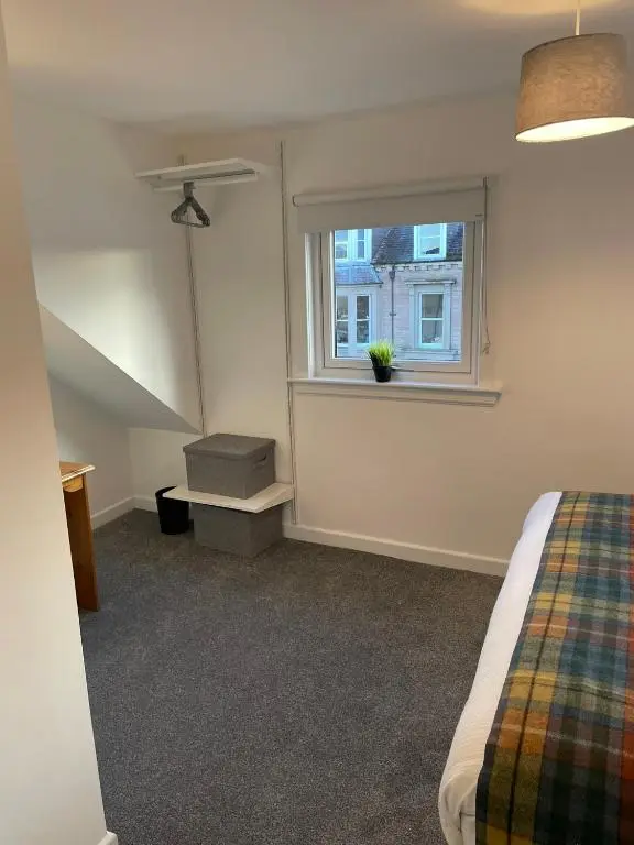a bedroom with a bed and a window at Tartan House in Inverness