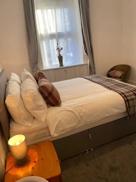a bed with pillows and a window in a room at Tartan House in Inverness
