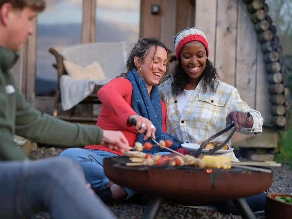 two women cooking food on a grill with a man at Glenshee Glamping in Glenshee