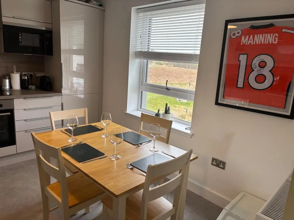 a kitchen with a wooden table with wine glasses on it at Gorgeous Dornoch apartment in Dornoch