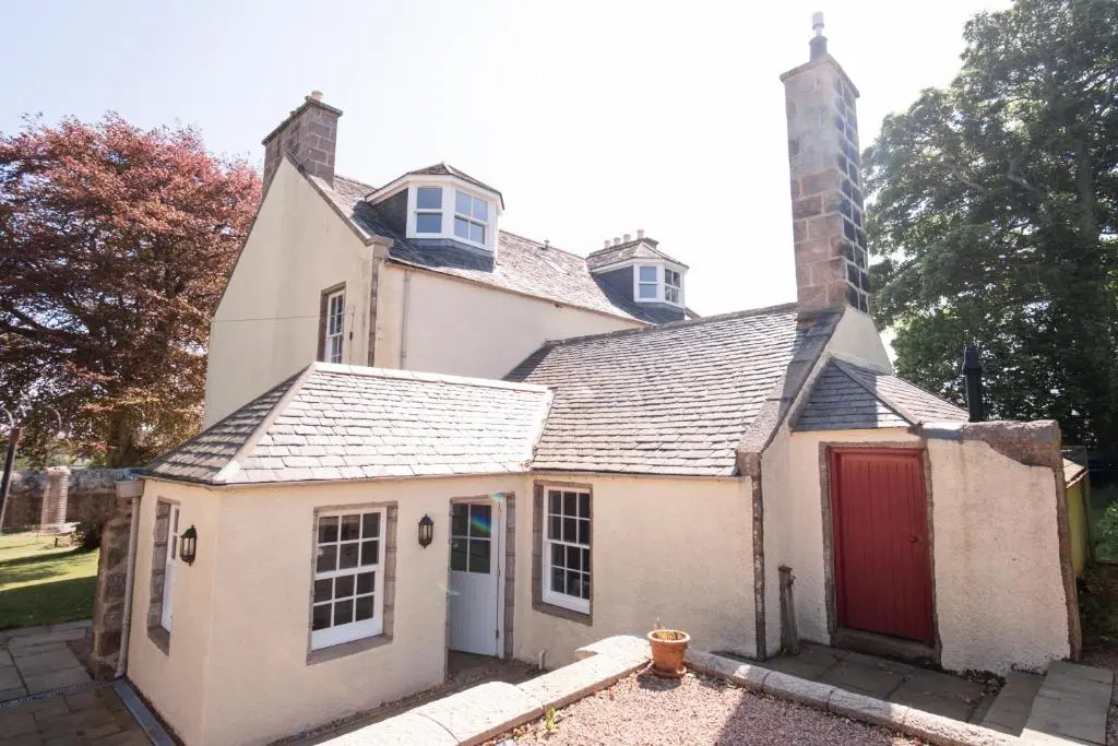 an old white house with a red door at The Old Manse Oyne in Oyne