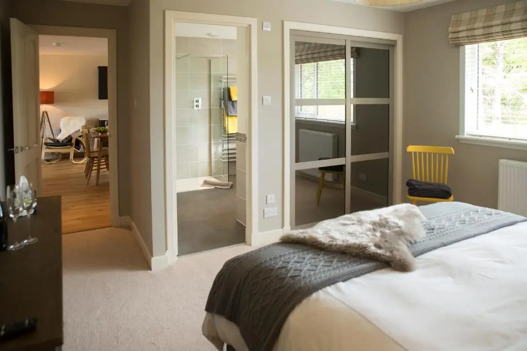 a bedroom with a bed and a walk in shower at Loch Cottage in Boat of Garten