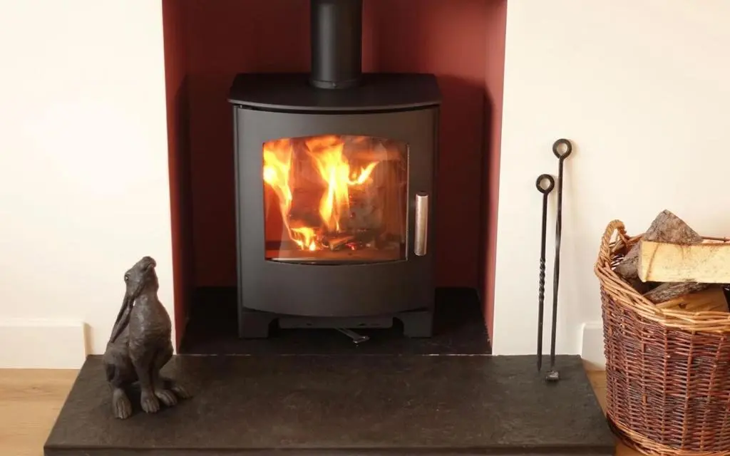 a fireplace with a cat sitting in front of it at Loch Cottage in Boat of Garten