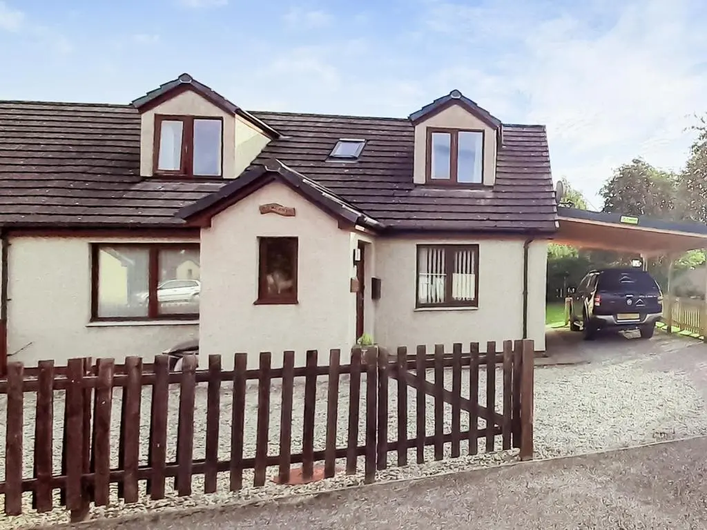 a house with a wooden fence in front of it at Rowlands in Aviemore