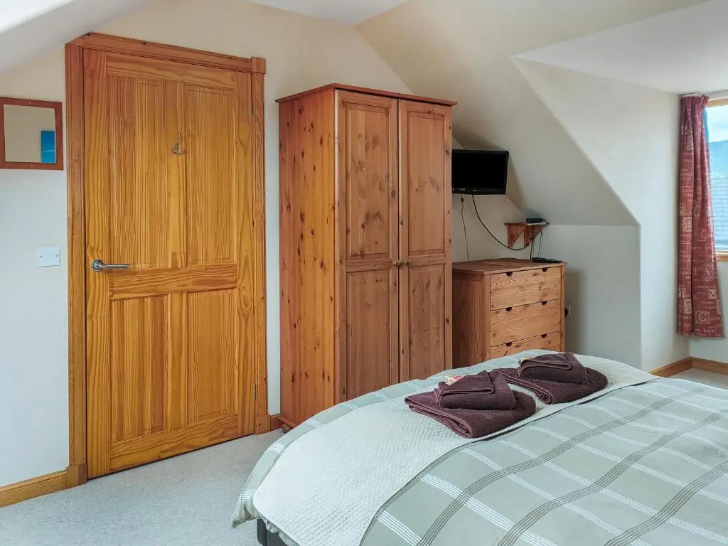 a bedroom with a bed and a wooden cabinet at Rowlands in Aviemore