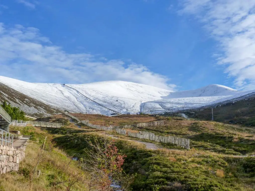 a snow covered mountain with a train in a field at Rowlands in Aviemore