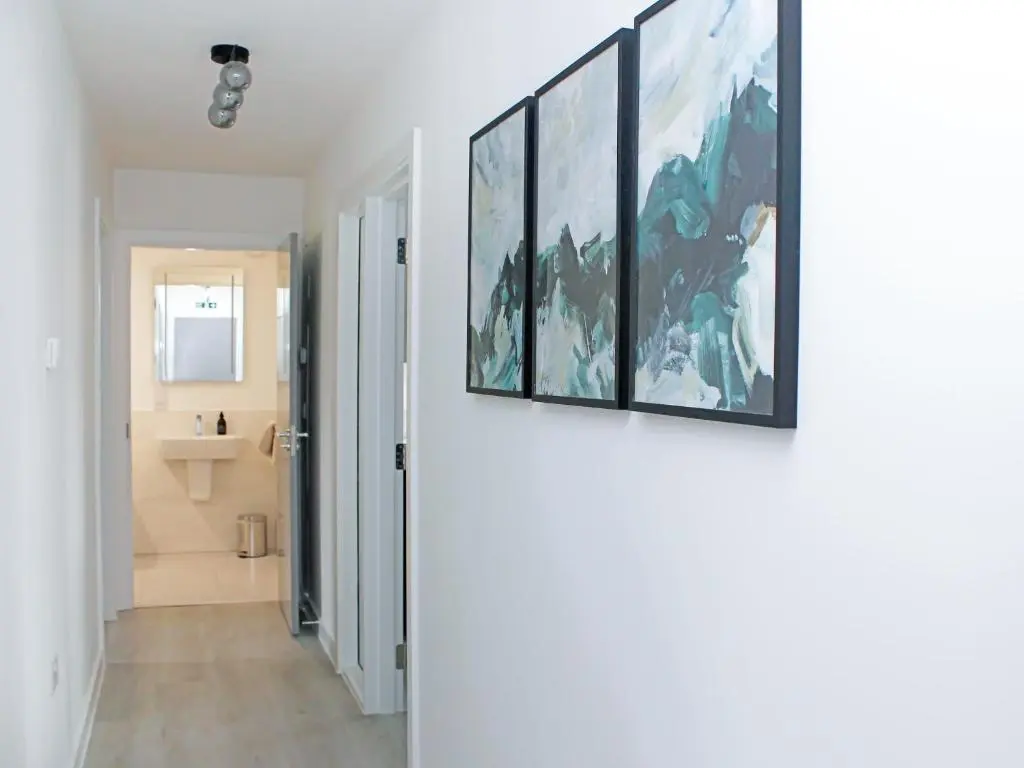 a hallway leading to a bathroom with two paintings on the wall at The Peaks in Aviemore