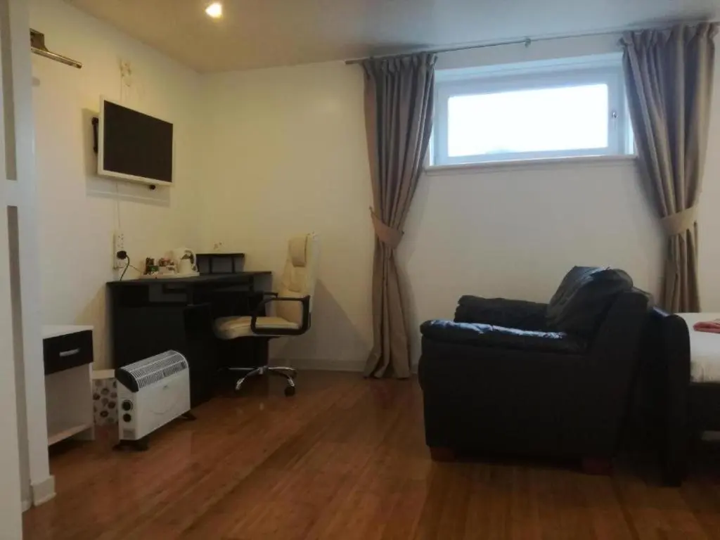a living room with a desk and a couch and a window at Ardenlea House Hotel B&b in Dyce