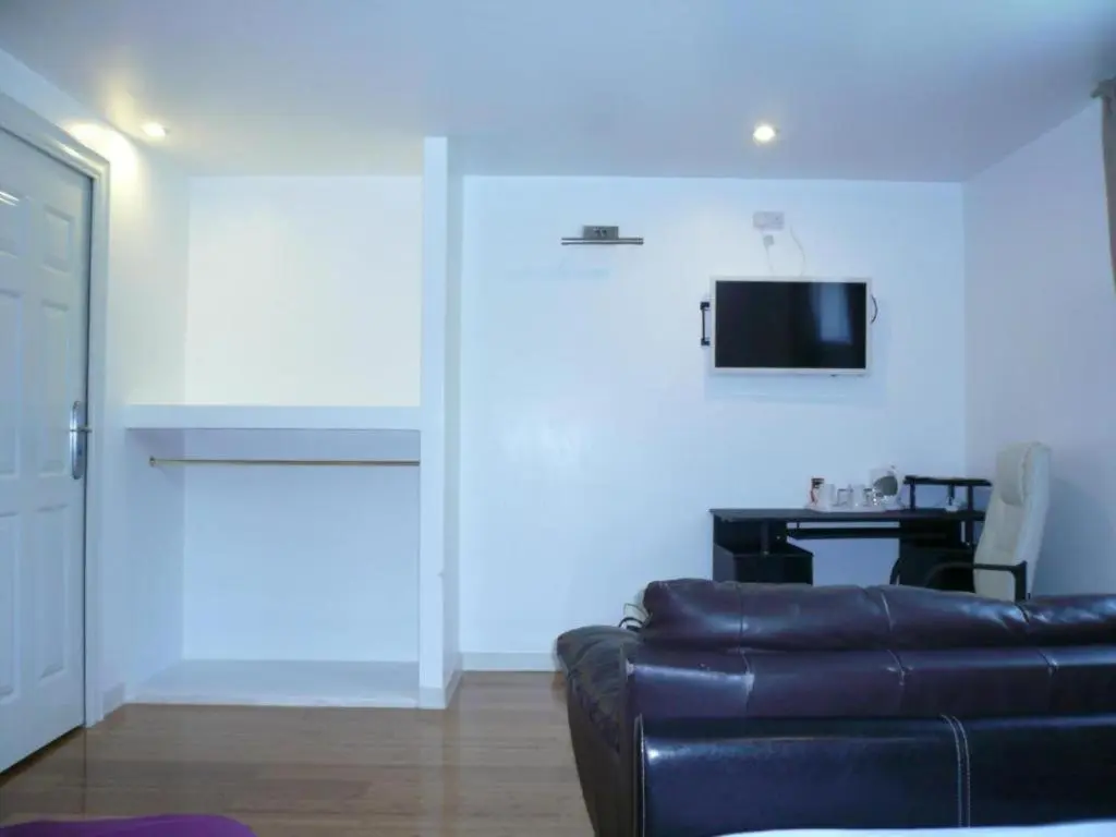 a living room with a couch and a tv on a wall at Ardenlea House Hotel B&b in Dyce