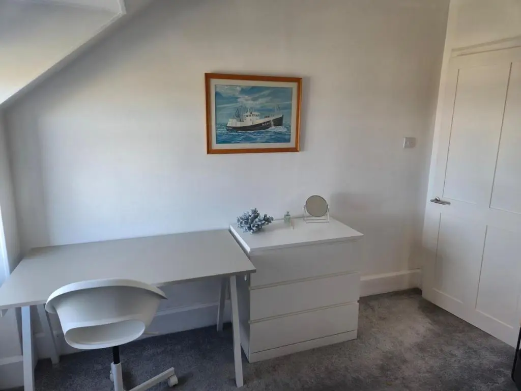 a white desk with a chair and a picture on the wall at Dalwhinnie in Buckie