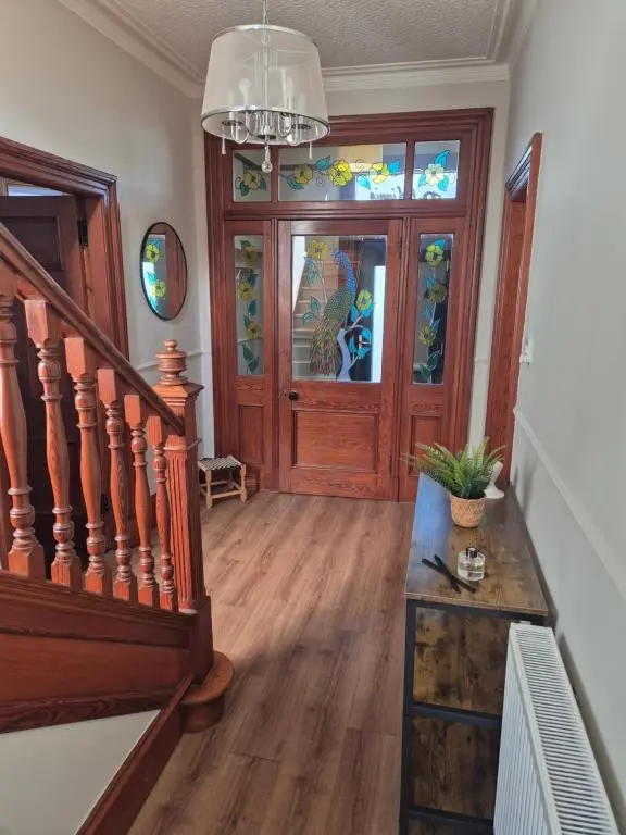 a hallway with a staircase and a stained glass door at Dalwhinnie in Buckie