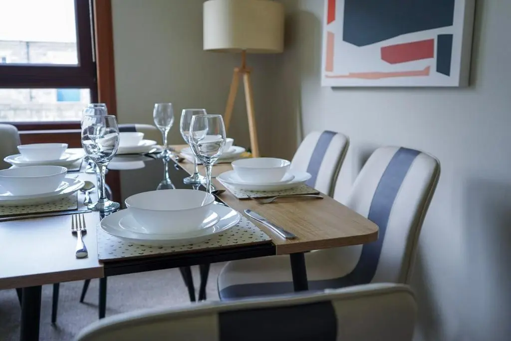 a dining room table with white plates and wine glasses at Rosehearty house - 3 bedroom in Rosehearty