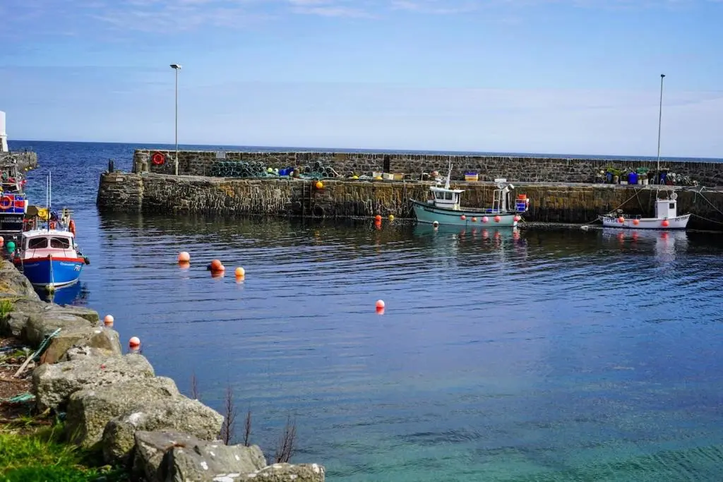 a group of boats in the water near a pier at Rosehearty house - 3 bedroom in Rosehearty