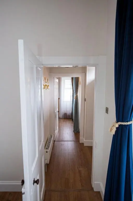 a hallway with a blue curtain and a hallway with a door at West Lodge, High Street in Aberlour
