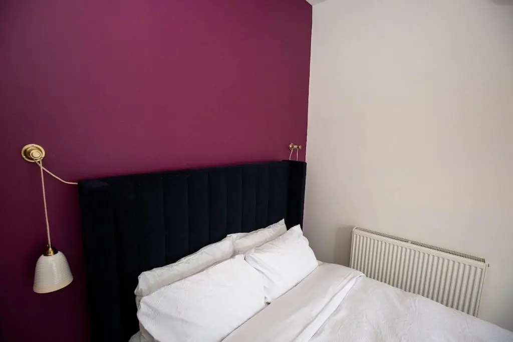 a bed with a black headboard and white pillows at West Lodge, High Street in Aberlour