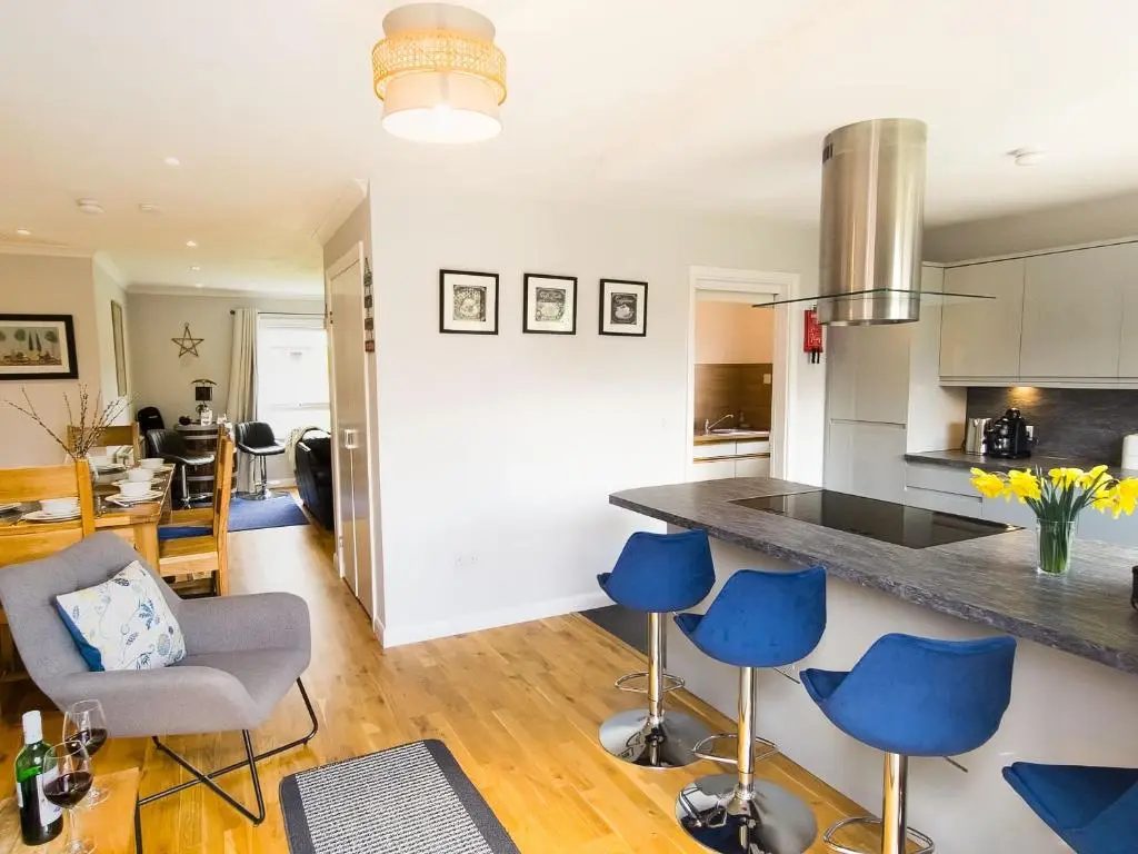 a kitchen and living room with blue chairs and a counter at Killiechangie House in Newtonmore