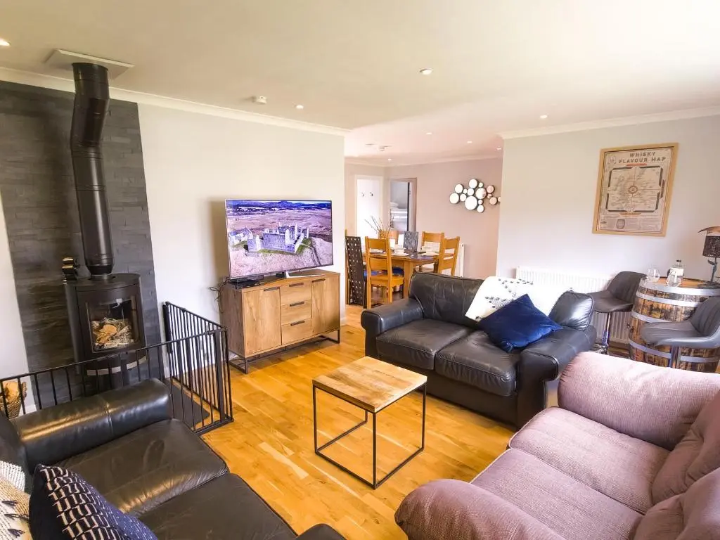 a living room with a couch and a fireplace at Killiechangie House in Newtonmore