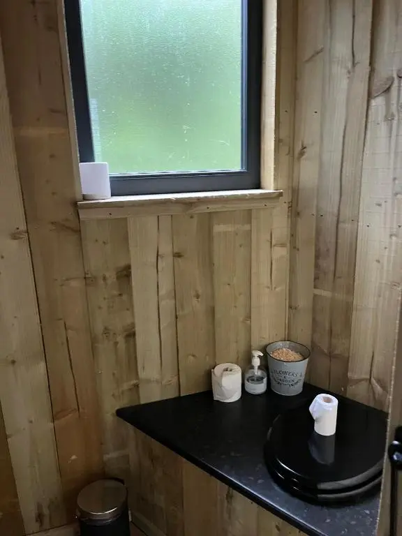 a bathroom with a black counter with a window at Treetops at Wildwoodz Off grid treehouse No electricity in Allangrange Station