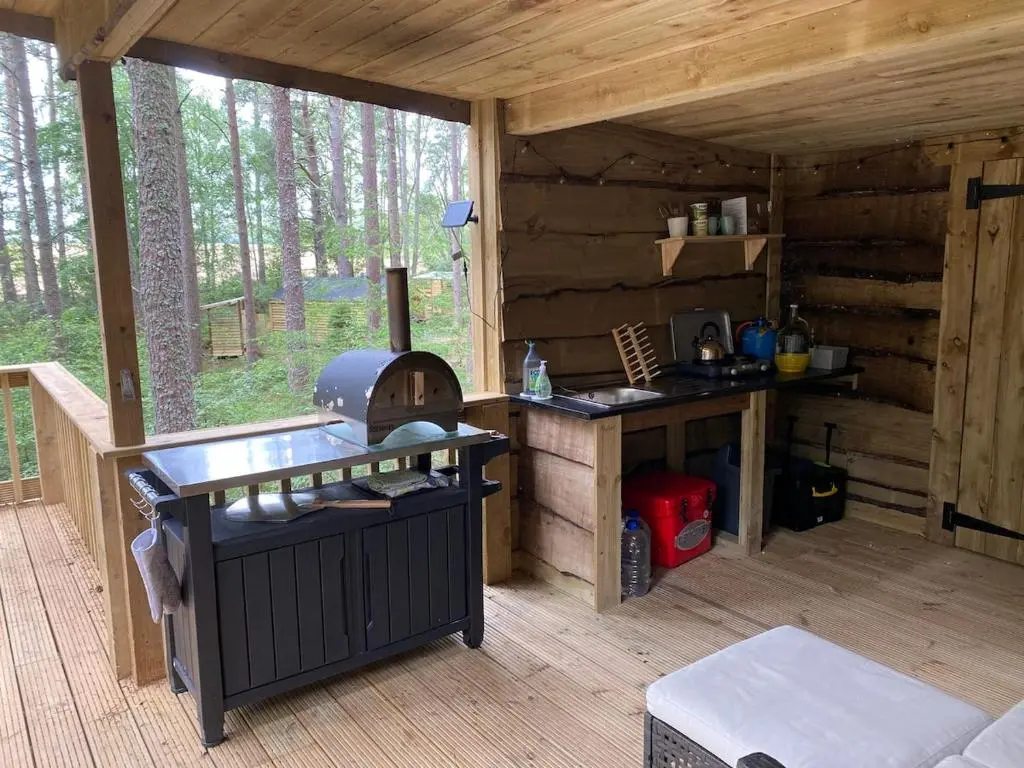 a kitchen in a log cabin with a stove at Treetops at Wildwoodz Off grid treehouse No electricity in Allangrange Station