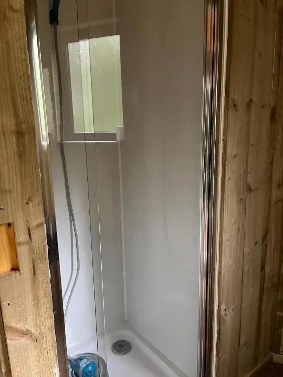 a shower with a glass door in a bathroom at Treetops at Wildwoodz Off grid treehouse No electricity in Allangrange Station