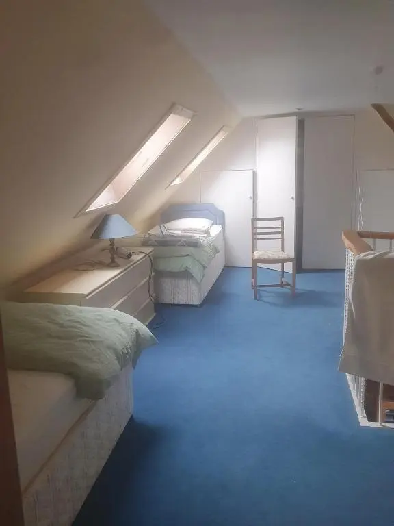 a attic bedroom with two beds and a chair at Idyllic beach cottage 56 Seatown Cullen in Cullen