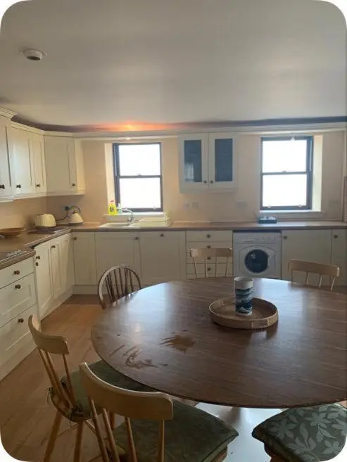 a kitchen with a wooden table and a table and chairs at Idyllic beach cottage 56 Seatown Cullen in Cullen