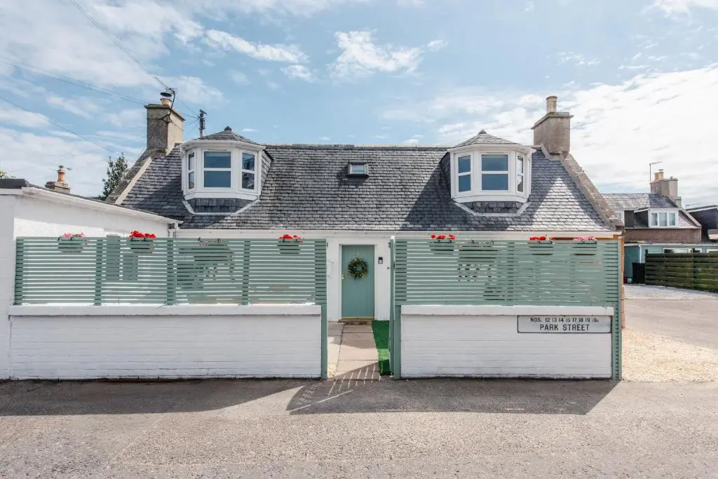 a green and white house with two garage doors at Keel Cottage & Dog Friendly in Nairn