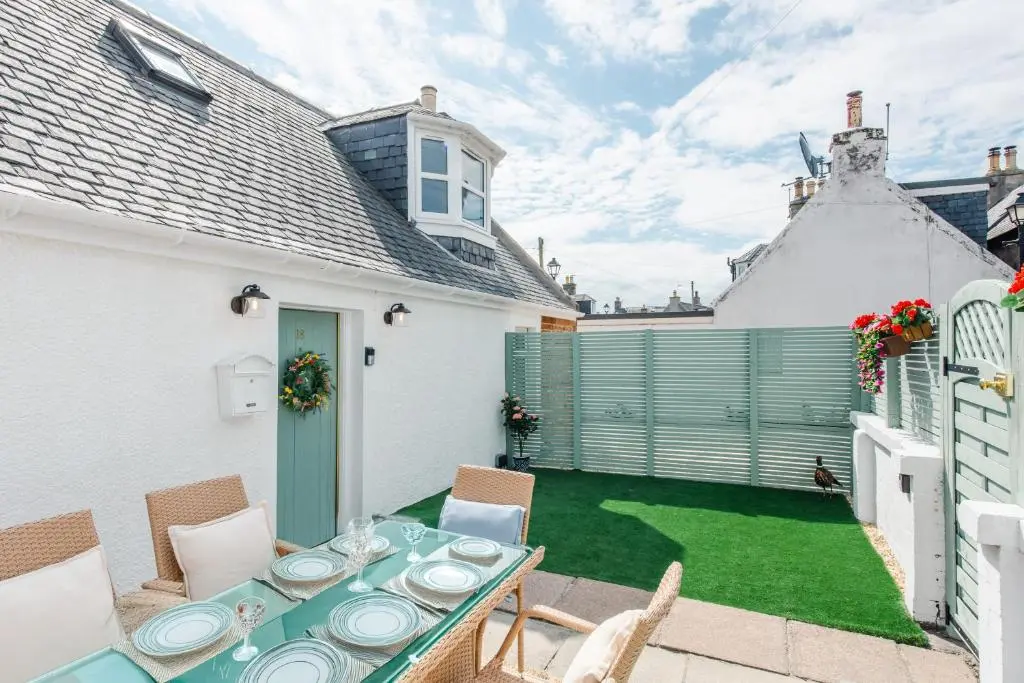 a patio with a table and chairs on a lawn at Keel Cottage & Dog Friendly in Nairn