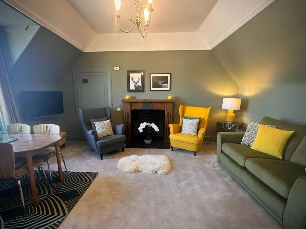 a living room with a couch and a table and chairs at Laughlin House in Inverness