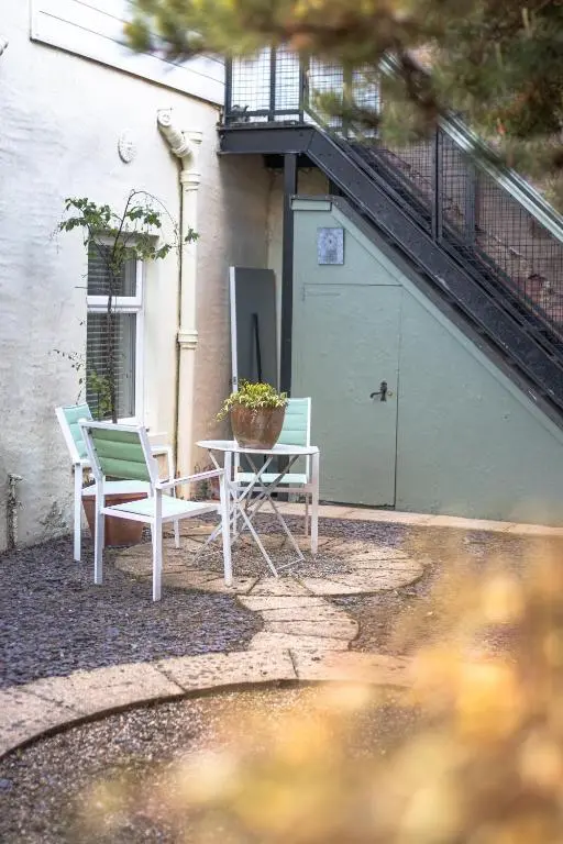 a patio with two chairs and a table next to a building at Laughlin House in Inverness
