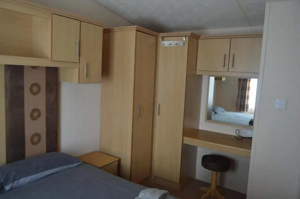 a small bedroom with a bed and a mirror at C5, The Old Mill Caravan Park, Brodie in Dyke