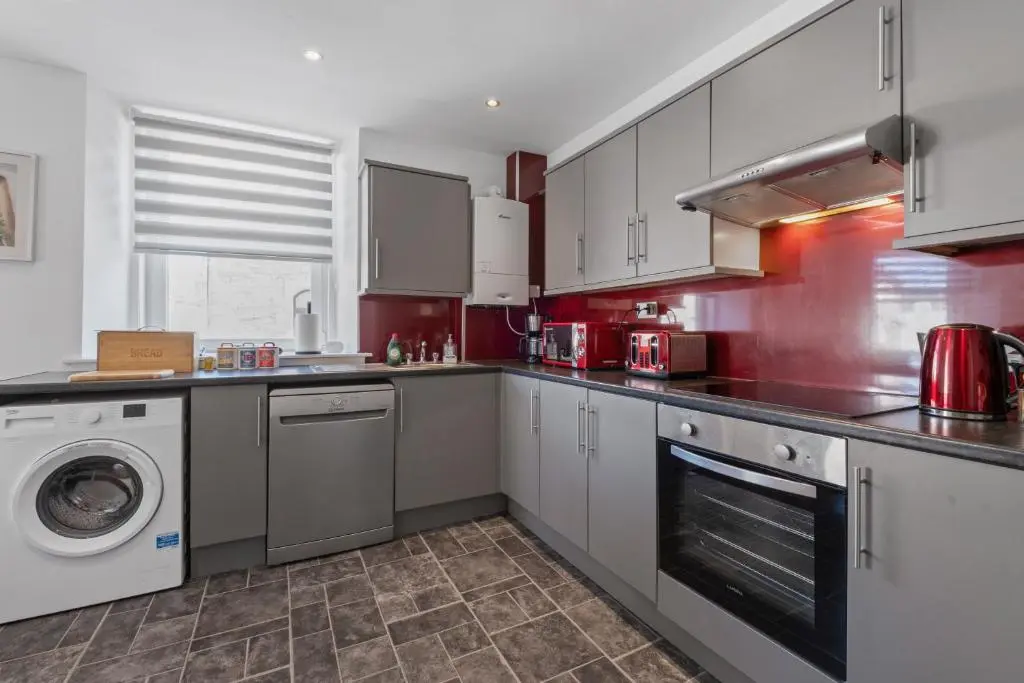a kitchen with white cabinets and a washer and dryer at Caledonian Buildings 20b stylish city centre apartment in Inverness
