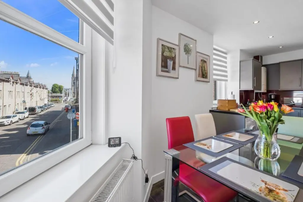 a kitchen and dining room with a table and a window at Caledonian Buildings 20b stylish city centre apartment in Inverness