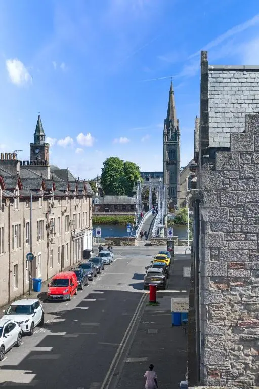 a city street with parked cars and a clock tower at Caledonian Buildings 20b stylish city centre apartment in Inverness