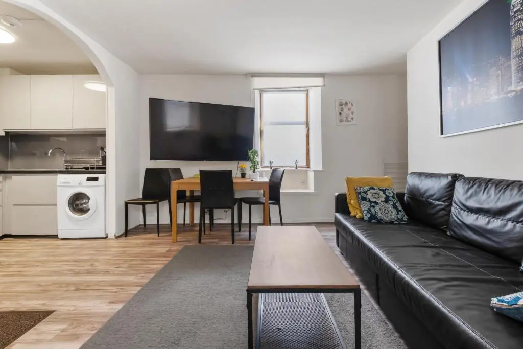 a living room with a black couch and a table at BTS 2 Bed Apart Inverness Centre in Inverness