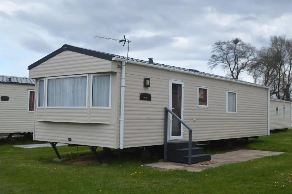a white mobile home with a staircase in a yard at B5 at The Old Mill Holiday Park in Dyke