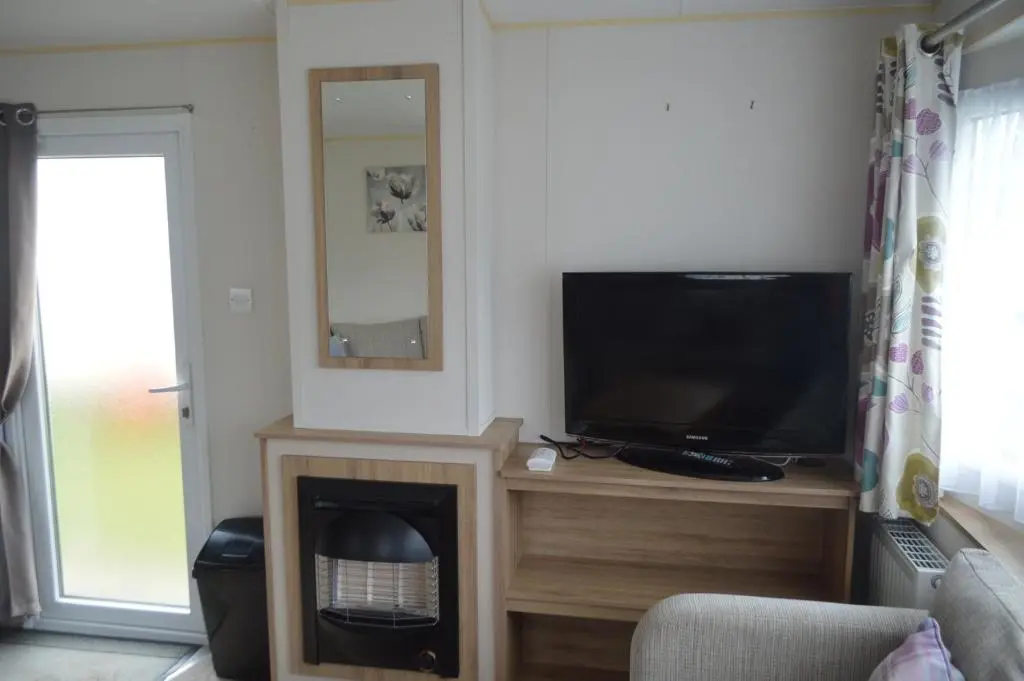 a living room with a television and a fireplace at B5 at The Old Mill Holiday Park in Dyke