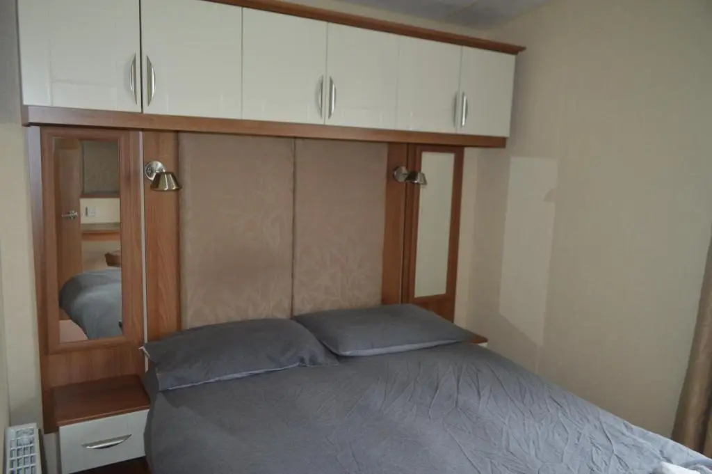 a bedroom with a bed with a cabinet above it at B8 at The Old Mill Holiday Park in Dyke