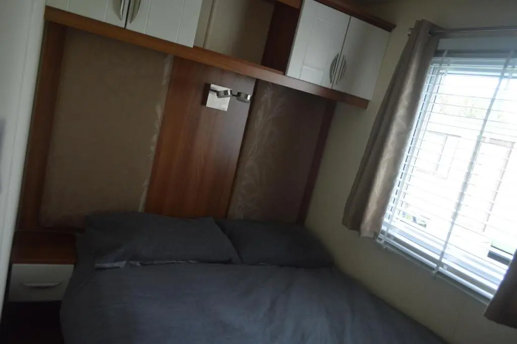 a bed in a small room with a window at B8 at The Old Mill Holiday Park in Dyke