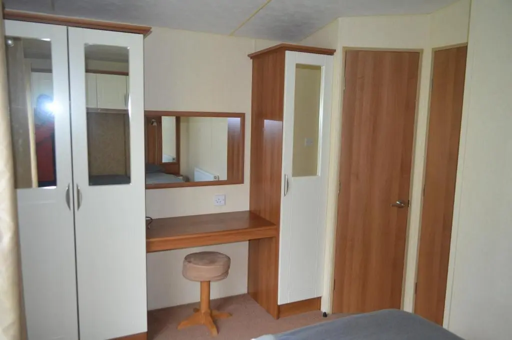 a bedroom with a desk and a mirror at B8 at The Old Mill Holiday Park in Dyke