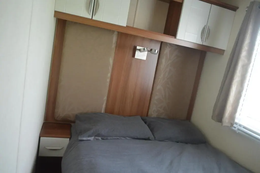 a bed with a wooden headboard in a bedroom at B8 at The Old Mill Holiday Park in Dyke