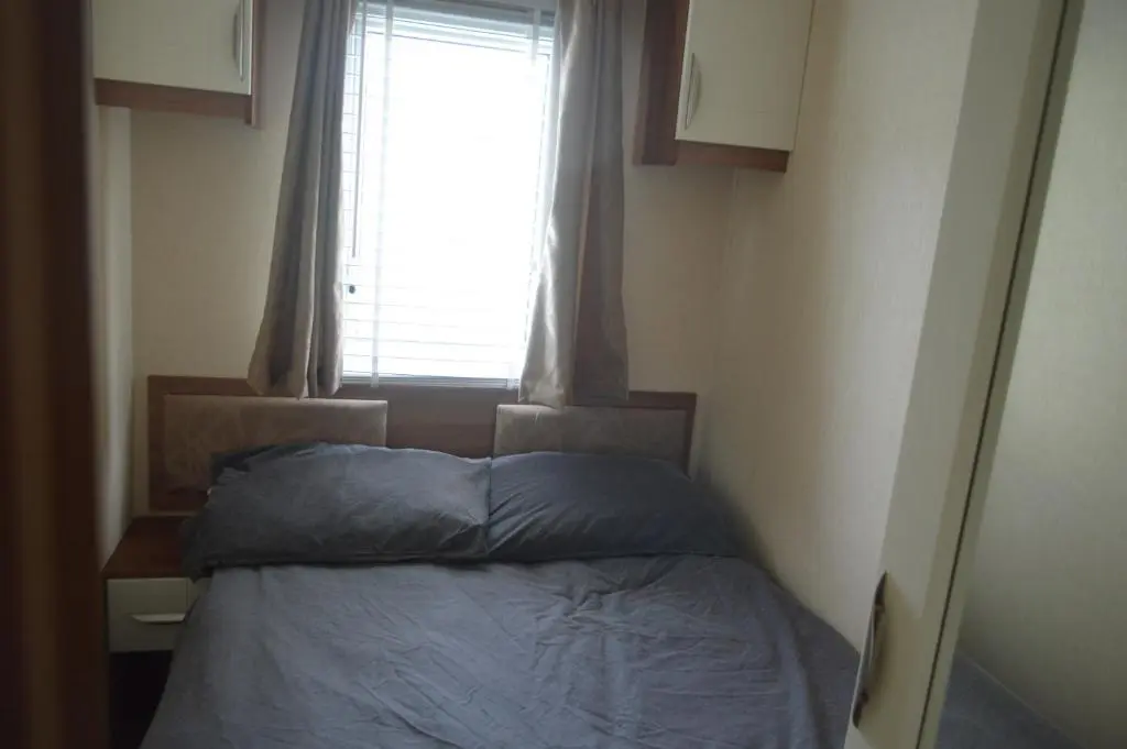 a bed in a small room with a window at B8 at The Old Mill Holiday Park in Dyke