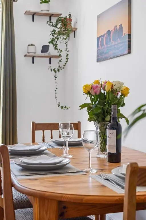 a dining room table with a bottle of wine and flowers at Inverness Riverside Apartment with Parking in Inverness
