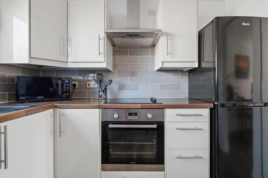 a kitchen with white cabinets and a stainless steel refrigerator at Inverness Riverside Apartment with Parking in Inverness