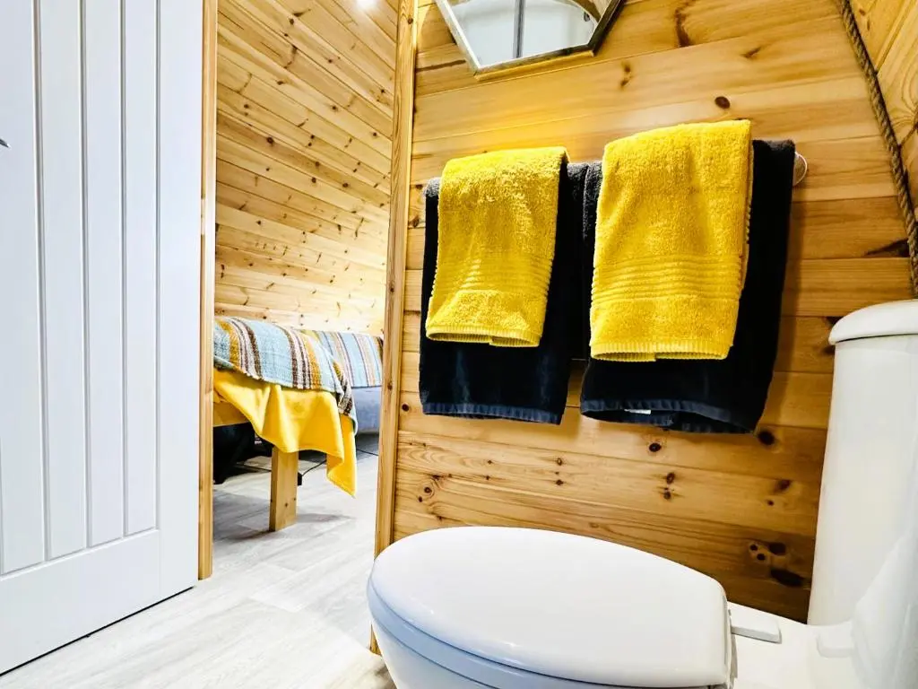 a bathroom with a toilet and yellow towels at Brora Escapes in Brora