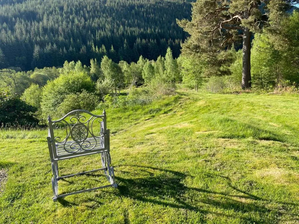 a bench sitting in the grass in a field at Glentromie Estate in Ruthven