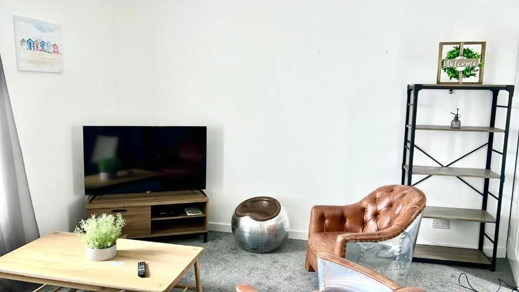 a living room with a chair and a table and a tv at Harbour View Hopeman in Hopeman