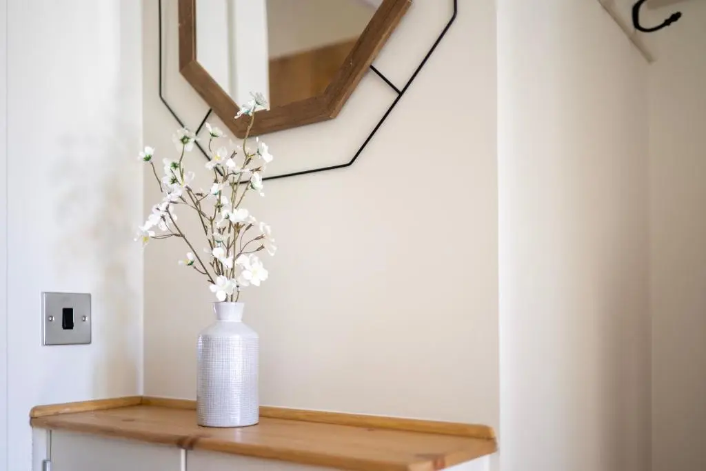 a white vase on a wooden table with a mirror at Firthview Fortrose in Fortrose