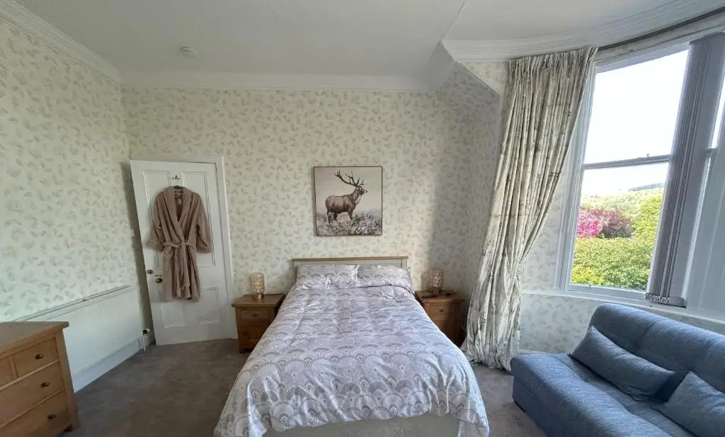 a bedroom with a bed and a couch and a window at Gruinard Guest House in Beauly